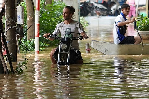 Vietnam Typhoon Yagi: A man pushes his motorbike in a flooded street